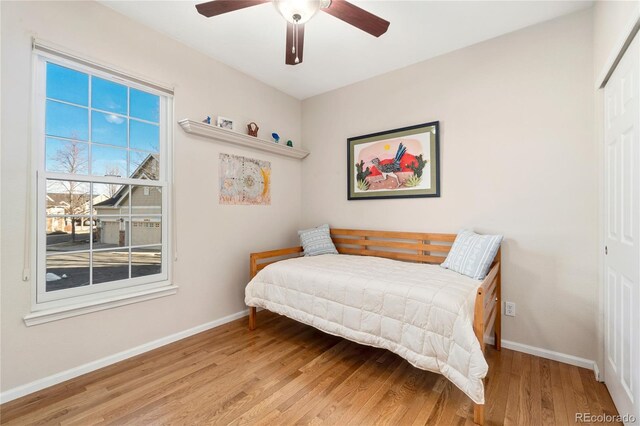 bedroom with light wood-style floors, a ceiling fan, baseboards, and a closet