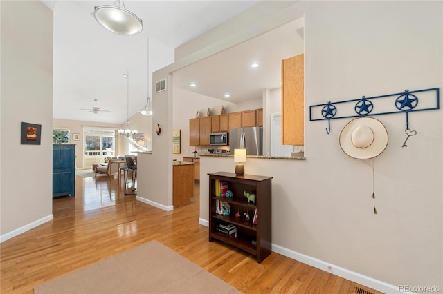 kitchen featuring brown cabinets, open floor plan, a peninsula, stainless steel appliances, and light countertops