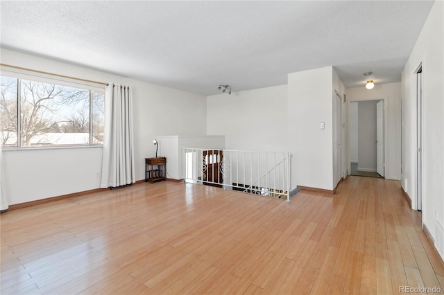unfurnished room with light hardwood / wood-style floors and a textured ceiling