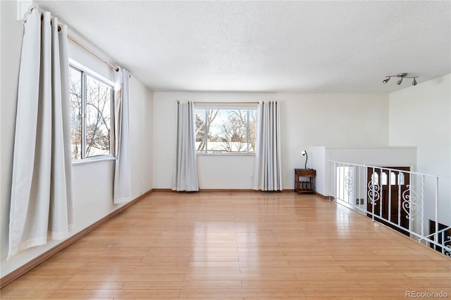 spare room featuring light hardwood / wood-style floors and a textured ceiling