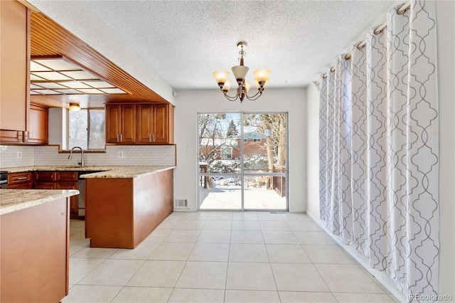 kitchen with light stone countertops, decorative light fixtures, backsplash, a chandelier, and light tile patterned floors