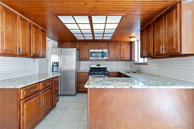 kitchen featuring stainless steel appliances, tasteful backsplash, sink, light stone counters, and light tile patterned floors