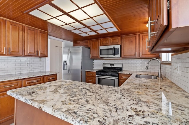 kitchen featuring sink, stainless steel appliances, light stone counters, and kitchen peninsula