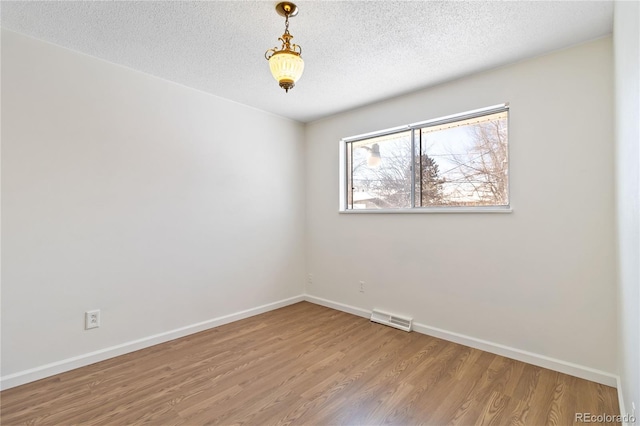 spare room featuring wood-type flooring and a textured ceiling