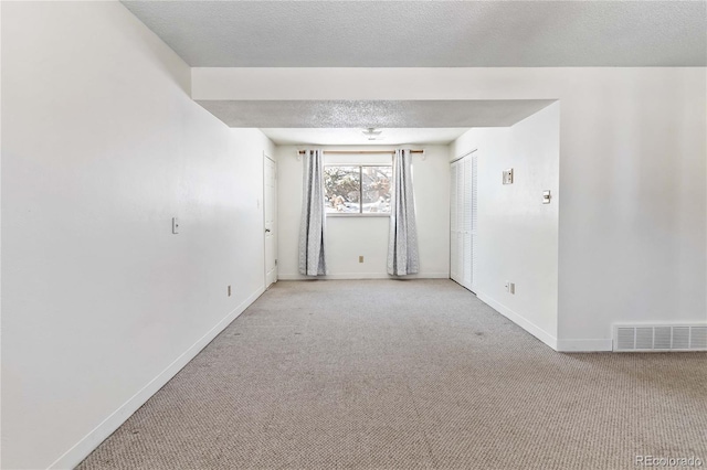 empty room with light colored carpet and a textured ceiling