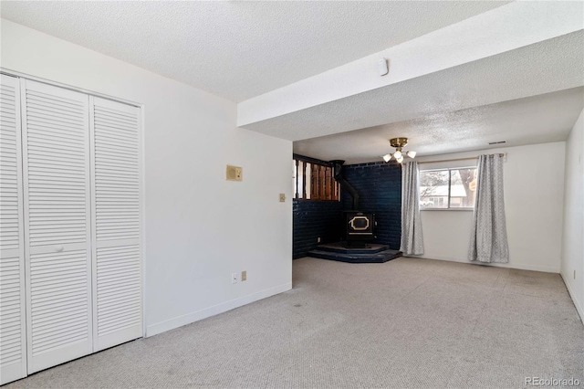 unfurnished bedroom featuring a closet, a wood stove, light carpet, and a textured ceiling