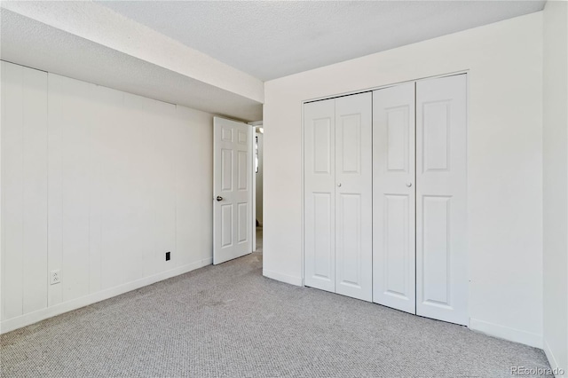 unfurnished bedroom with a closet, light colored carpet, and a textured ceiling