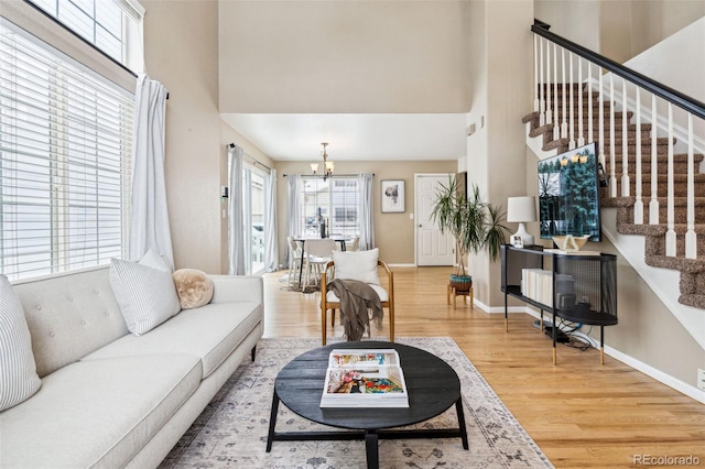 living room with a notable chandelier, hardwood / wood-style flooring, and a towering ceiling