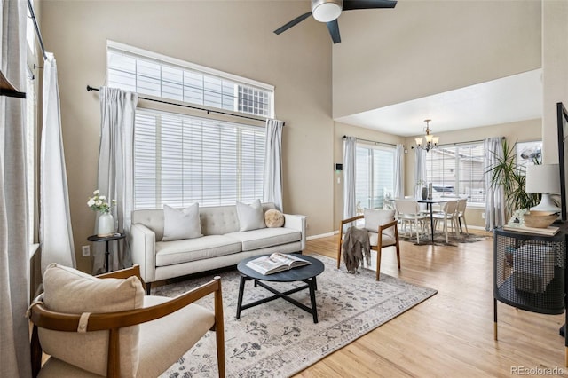 living room with hardwood / wood-style flooring, a towering ceiling, and ceiling fan with notable chandelier