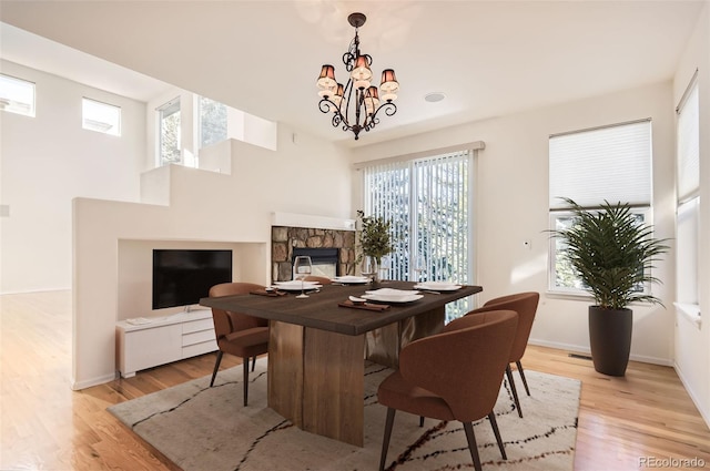 dining room with a chandelier, light hardwood / wood-style floors, and a stone fireplace