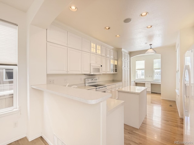 kitchen with white appliances, kitchen peninsula, and white cabinetry