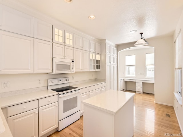 kitchen featuring white appliances, light hardwood / wood-style floors, a center island, pendant lighting, and white cabinetry