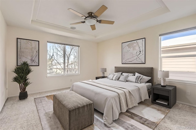 bedroom featuring multiple windows, ceiling fan, and a tray ceiling