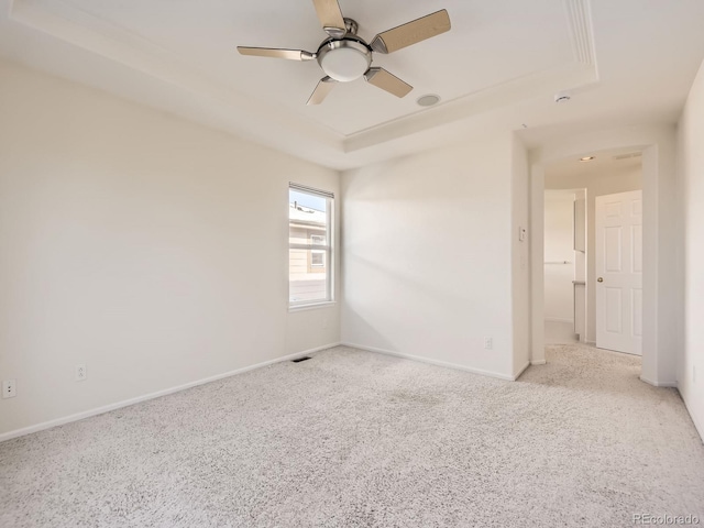 carpeted spare room with ceiling fan and a tray ceiling