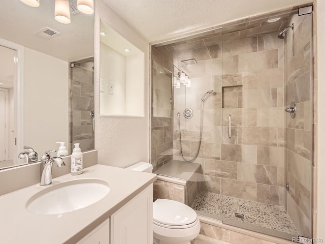 bathroom with toilet, a textured ceiling, a shower with shower door, and vanity