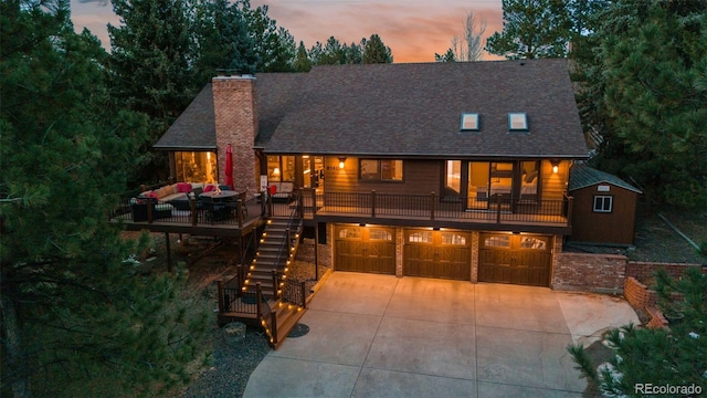 view of front of house with stairs, concrete driveway, an attached garage, brick siding, and a chimney