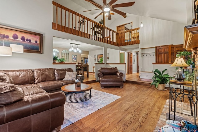 living room featuring ceiling fan with notable chandelier, high vaulted ceiling, and wood finished floors