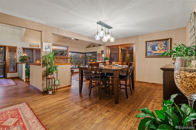 dining area with a textured ceiling, an inviting chandelier, and wood finished floors