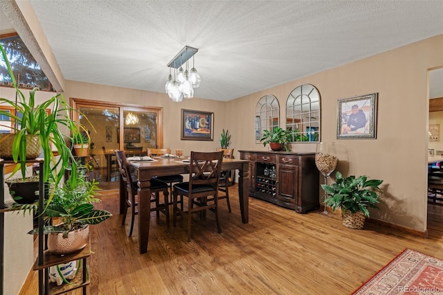 dining space with light wood-style floors and a textured ceiling