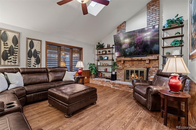 living room with ceiling fan, wood finished floors, a fireplace, and vaulted ceiling