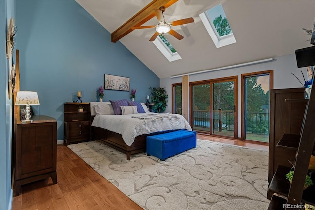 bedroom featuring beamed ceiling, high vaulted ceiling, access to outside, wood finished floors, and a skylight