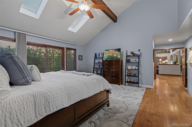 bedroom featuring baseboards, beam ceiling, a skylight, light wood-style floors, and high vaulted ceiling