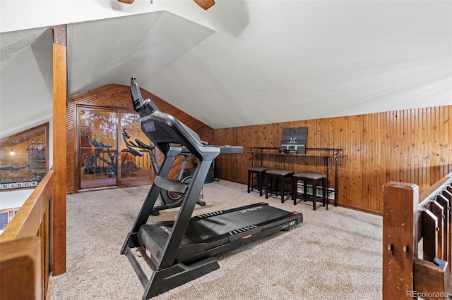 exercise area featuring lofted ceiling, wooden walls, carpet flooring, and ceiling fan