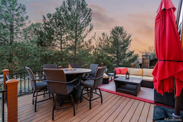 deck at dusk featuring an outdoor living space with a fire pit and outdoor dining area