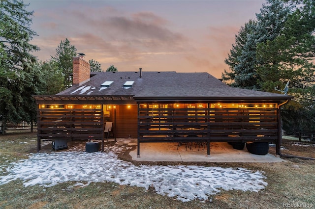 back of property with a patio, roof with shingles, and a chimney