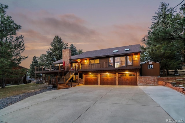 view of front facade with a balcony, a chimney, stairs, concrete driveway, and a garage