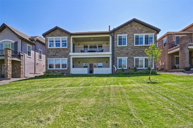 12121 Bryant St, Westminster, CO 80234 - view of front of house featuring stone siding, a balcony, a front lawn, and stucco siding