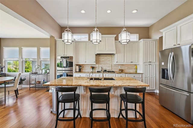12121 Bryant St, Westminster, CO 80234 - kitchen with stainless steel appliances, backsplash, an island with sink, white cabinetry, and light stone countertops