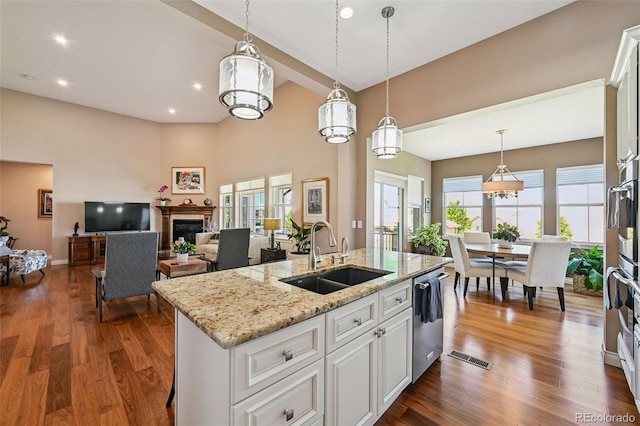 12121 Bryant St, Westminster, CO 80234 - kitchen with dishwasher, a fireplace, pendant lighting, dark wood-type flooring, and white cabinets