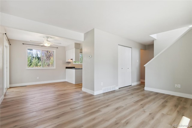 unfurnished living room featuring ceiling fan and light wood-type flooring