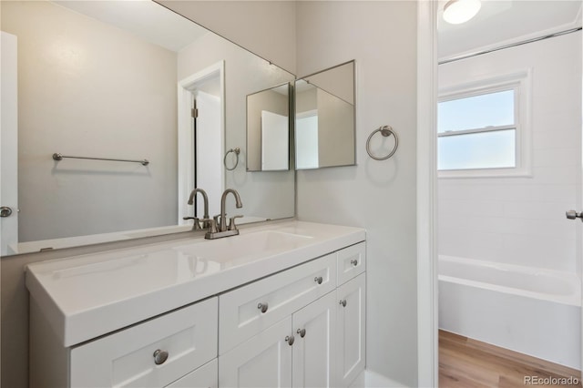 bathroom with hardwood / wood-style flooring, vanity, and a bathing tub