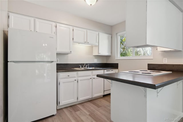 kitchen featuring a kitchen bar, kitchen peninsula, white appliances, sink, and white cabinets