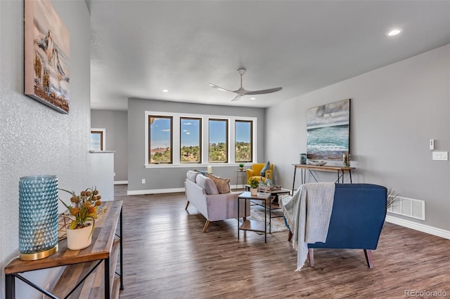 living room featuring dark wood-type flooring and ceiling fan