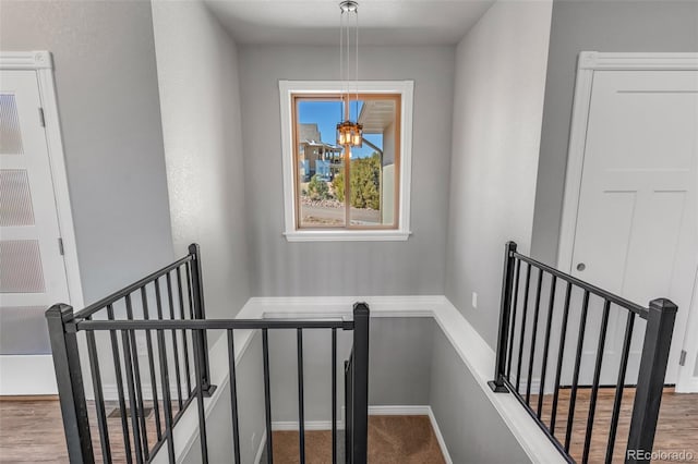 staircase with wood-type flooring and a notable chandelier