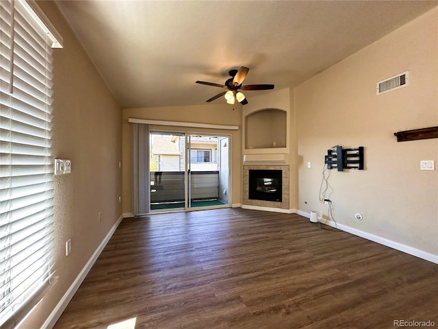 unfurnished living room featuring dark wood-type flooring, ceiling fan, a tile fireplace, and vaulted ceiling