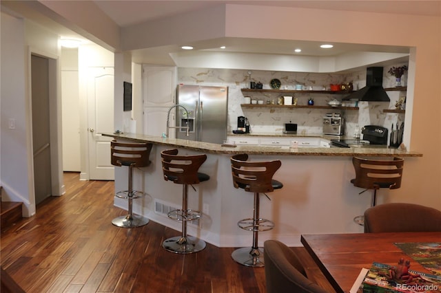 8747 Mesquite Row, Lone Tree, CO 80124 - kitchen with stainless steel fridge with ice dispenser, wall chimney range hood, stove, tasteful backsplash, and wood finished floors