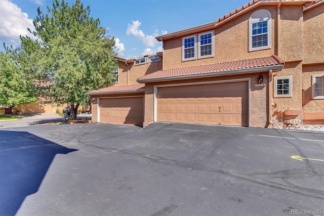 8747 Mesquite Row, Lone Tree, CO 80124 - multi unit property featuring a tile roof, a garage, stucco siding, and asphalt driveway