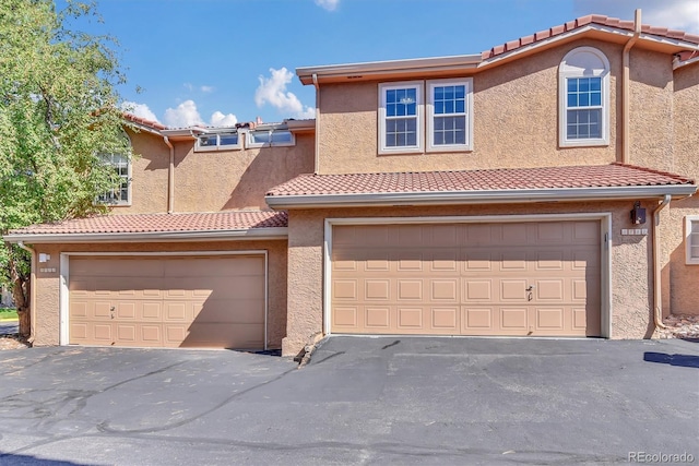 8747 Mesquite Row, Lone Tree, CO 80124 - townhome / multi-family property featuring stucco siding, a tiled roof, an attached garage, and asphalt driveway