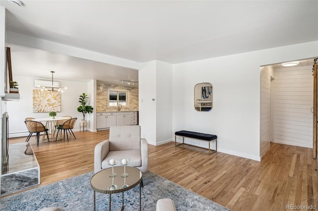 6170 Estes Ct, Arvada, CO 80004 - living room with baseboards, a wall mounted air conditioner, rail lighting, and light wood-type flooring