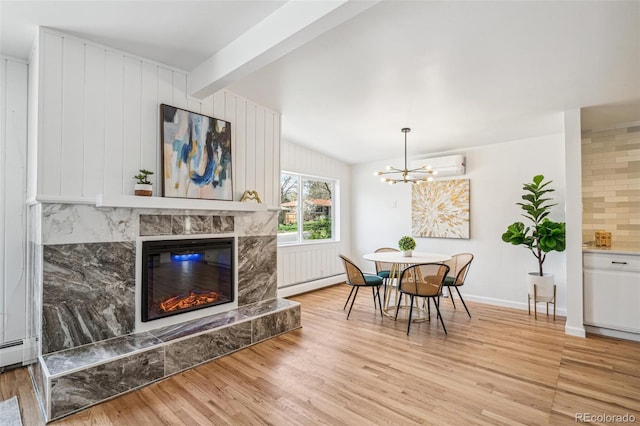 6170 Estes Ct, Arvada, CO 80004 - dining space featuring a baseboard radiator, light wood finished floors, a chandelier, vaulted ceiling with beams, and a premium fireplace