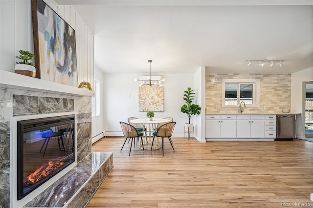6170 Estes Ct, Arvada, CO 80004 - dining room with an inviting chandelier, a baseboard radiator, light wood-style flooring, and a high end fireplace