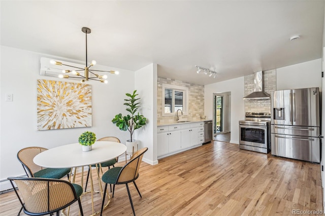 6170 Estes Ct, Arvada, CO 80004 - kitchen with appliances with stainless steel finishes, a sink, light countertops, wall chimney exhaust hood, and light wood-type flooring