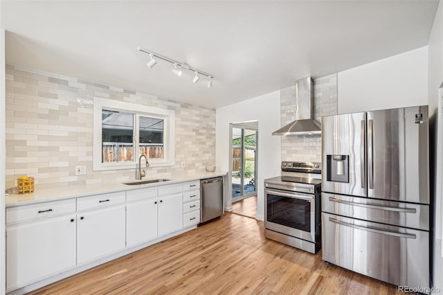 6170 Estes Ct, Arvada, CO 80004 - kitchen with wall chimney range hood, light countertops, tasteful backsplash, a sink, and appliances with stainless steel finishes