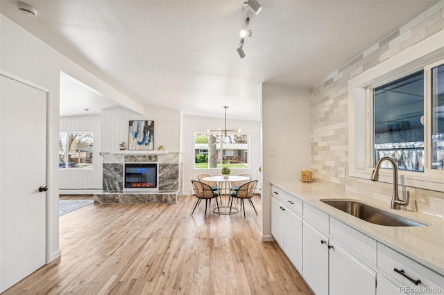 6170 Estes Ct, Arvada, CO 80004 - kitchen featuring a sink, light wood-style floors, white cabinetry, and a premium fireplace