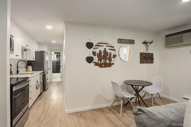 336 N Grant St Unit 206, Denver, CO 80203 - kitchen featuring white cabinets, appliances with stainless steel finishes, a sink, light countertops, and an AC wall unit