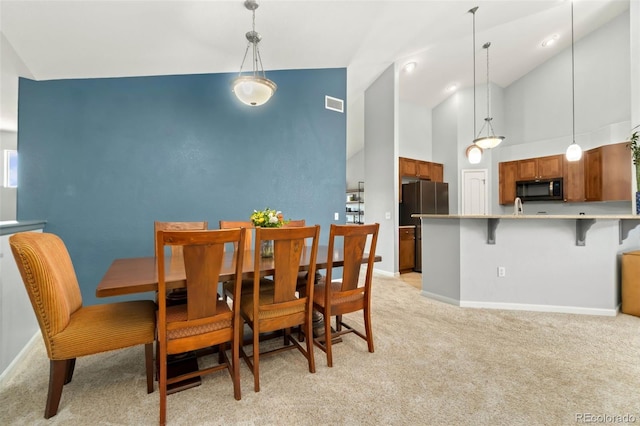 dining space with visible vents, light carpet, high vaulted ceiling, and baseboards